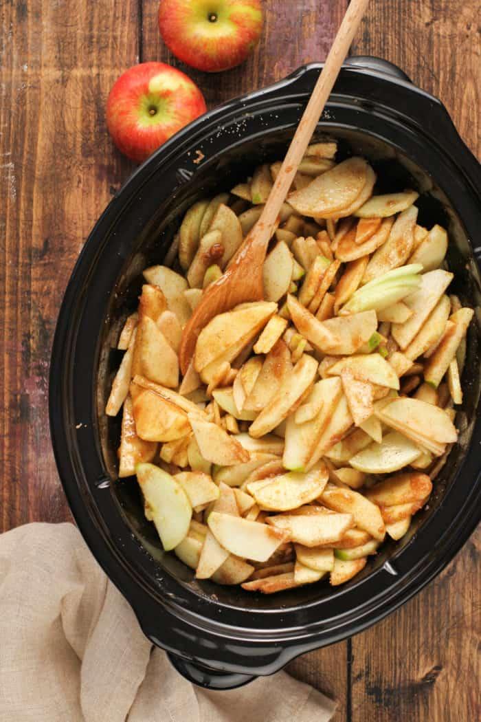 close-up of sliced apples being tossed with spices and honey in a mixing bowl
