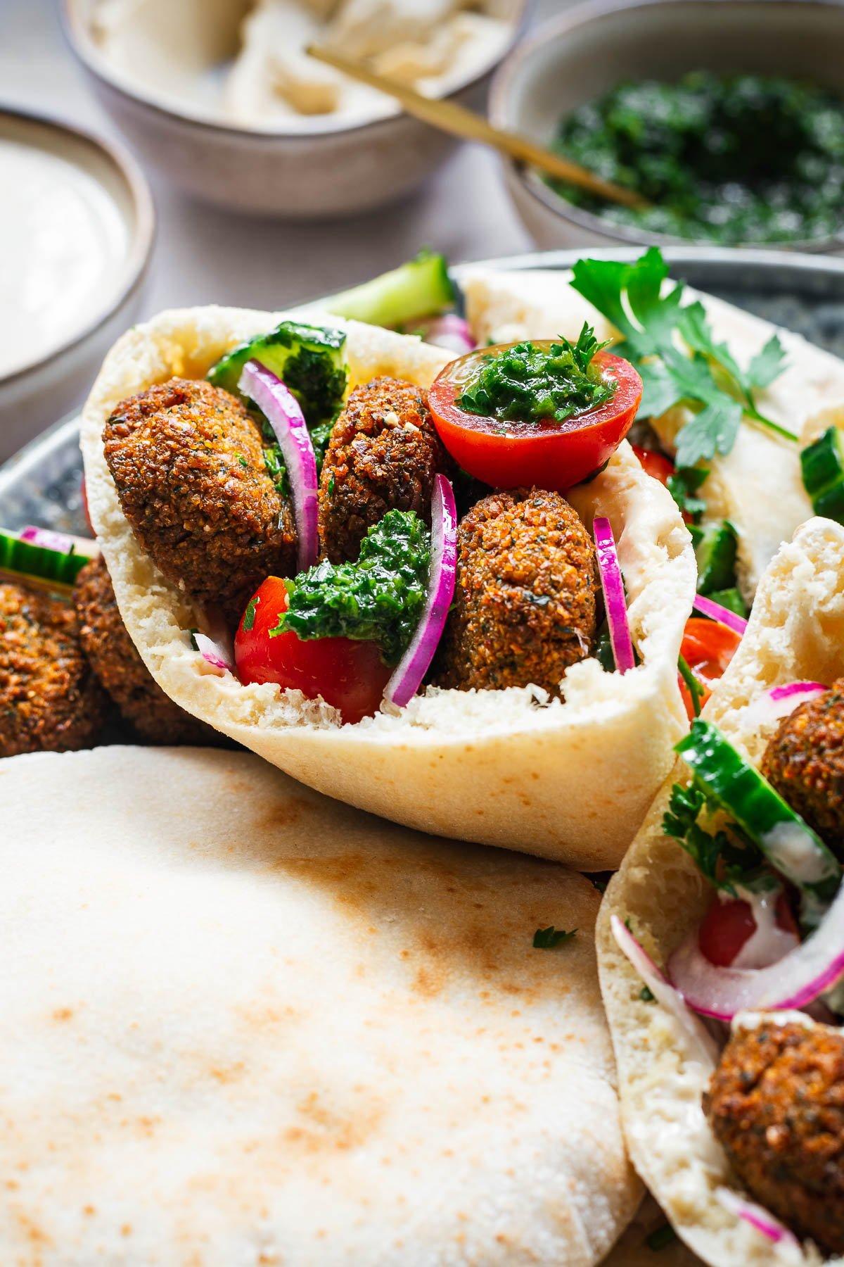 falafel served in a pita with tahini sauce, hummus, and chopped vegetables