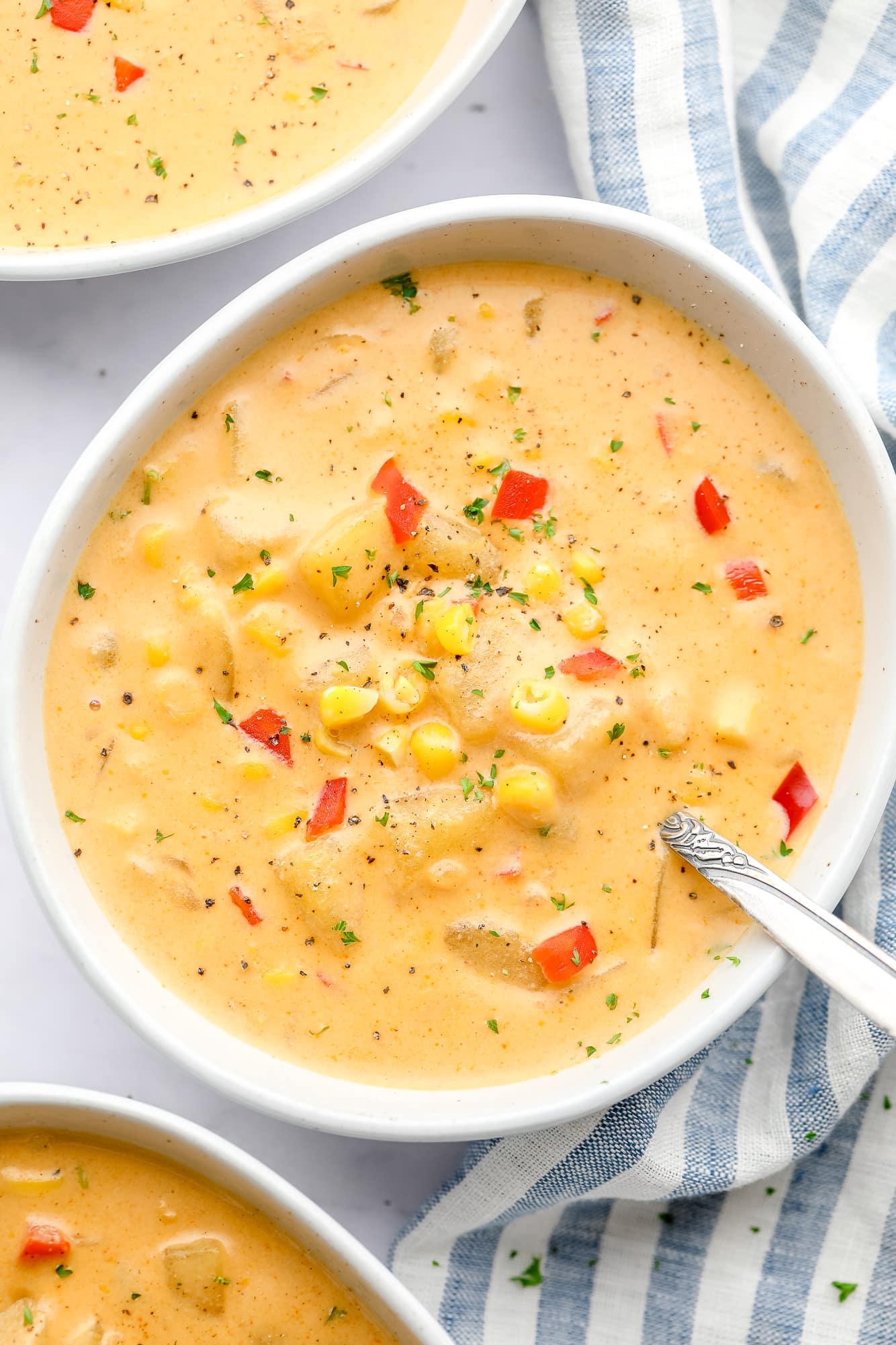 A person happily eating a bowl of vegan corn and cheese chowder