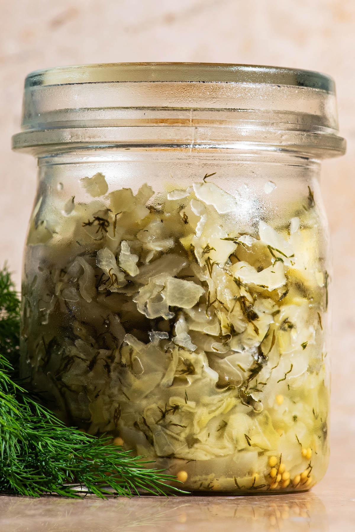 Close-up of Glasswort and Sauerkraut being tossed together in a stainless steel bowl.