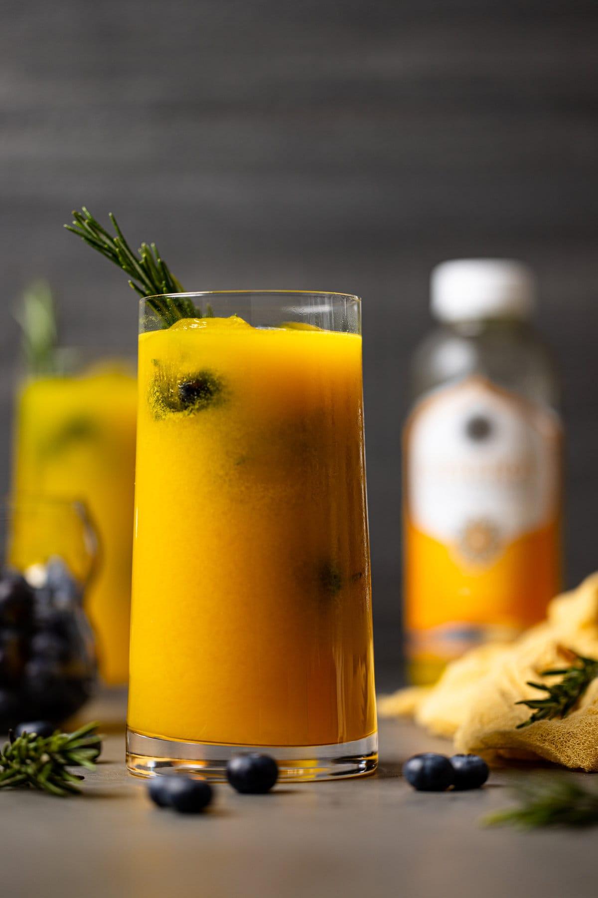 Refreshing Mango Peach Kombucha Mocktail in a highball glass with ice and fruit garnish