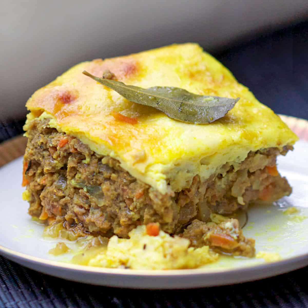 Close-up of a slice of bobotie, showing the layers of meat and custard