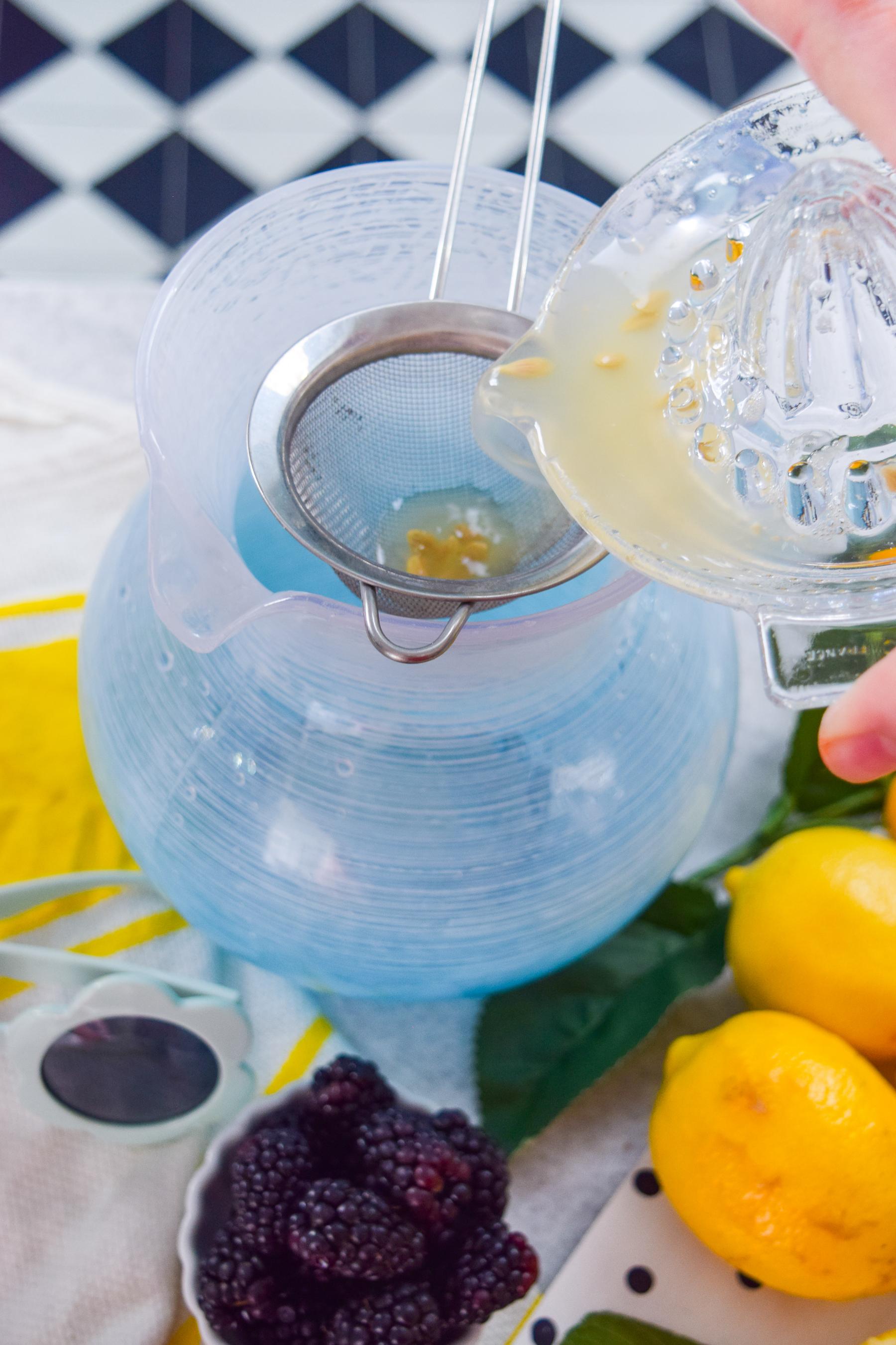 pitcher of blackberry mint lemonade being poured into a glass