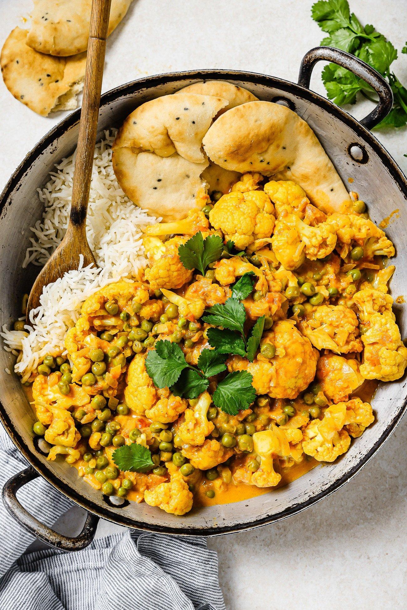 overhead shot of a pot of curried chickpea cauliflower rice simmering on a stove