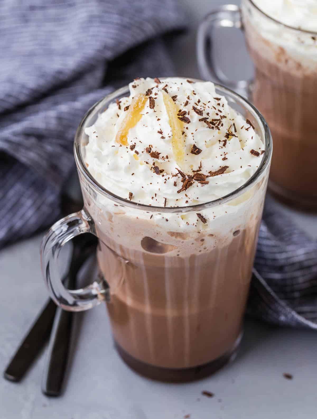 steaming mug of pear ginger hot chocolate with whipped cream and a dusting of cocoa powder