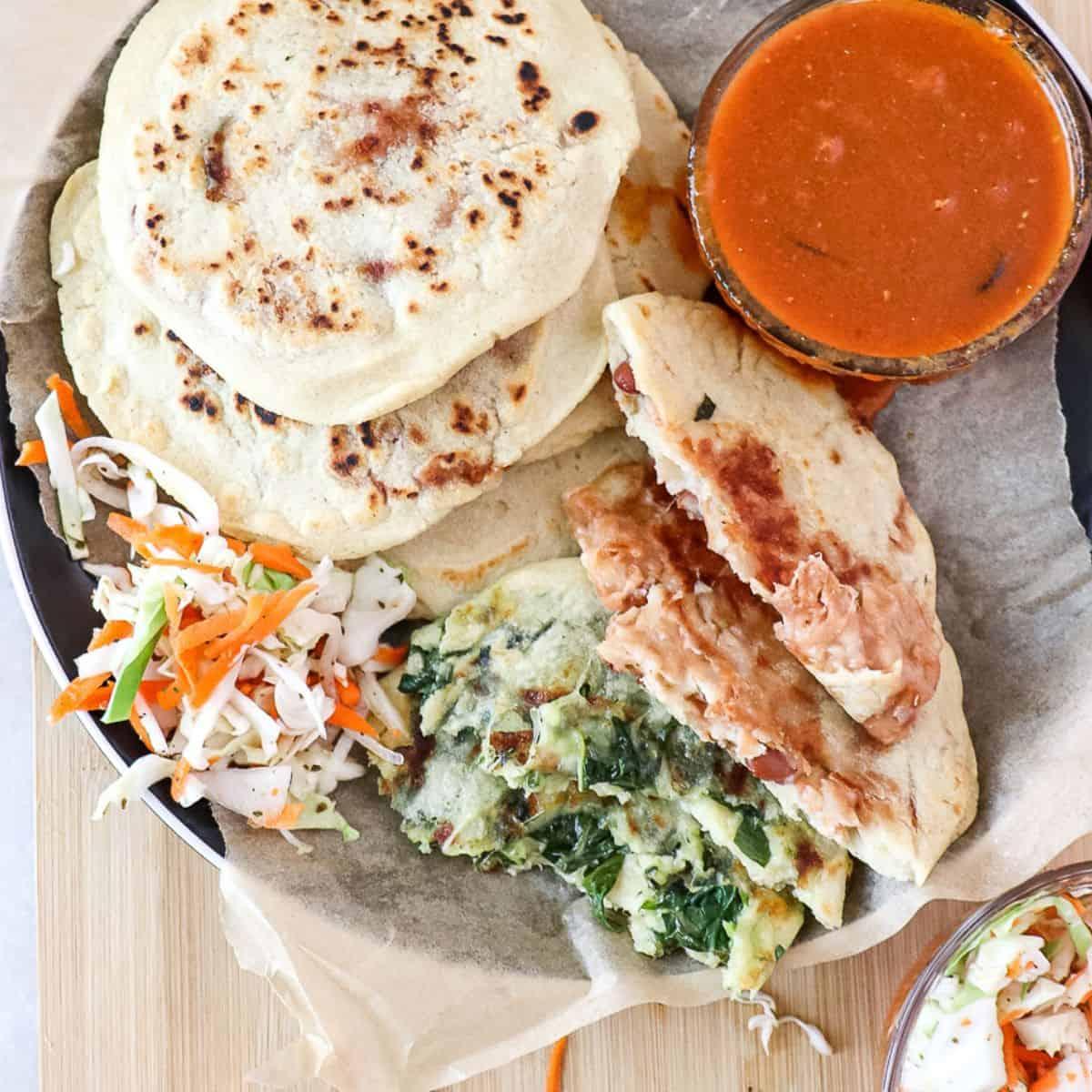 a platter of smoked brisket pupusas with curtido and salsa, ready to be served