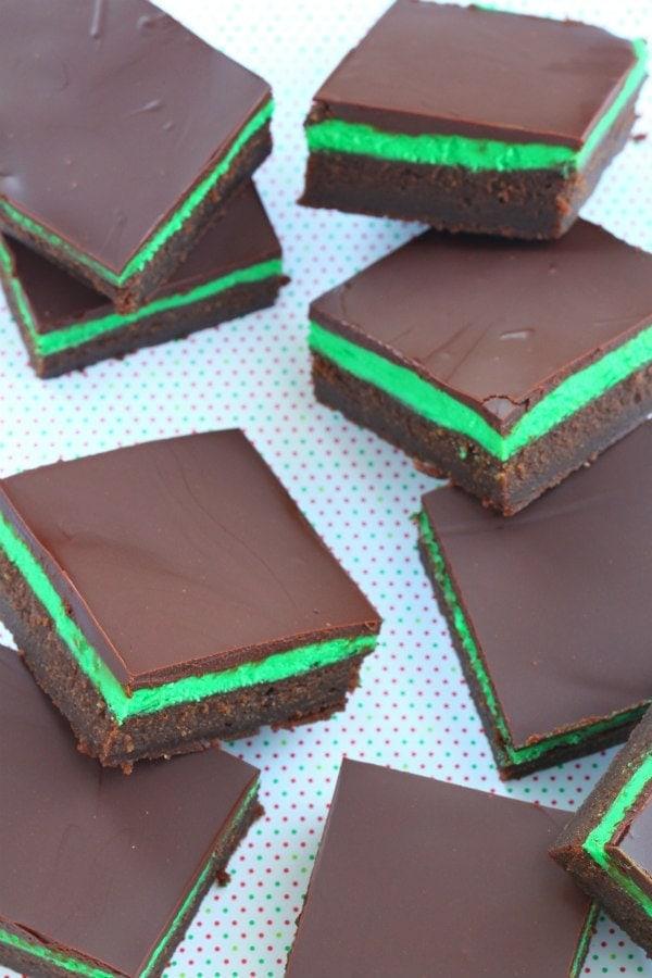 Overhead shot of layers of mint chocolate squares in a baking pan, showing the crust, mint filling, and chocolate topping