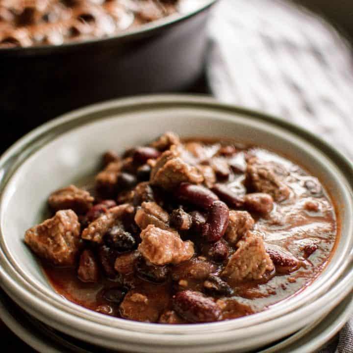 Close-up of tender beef chunks in a rich chili garlic stew, with visible garlic and chili flakes