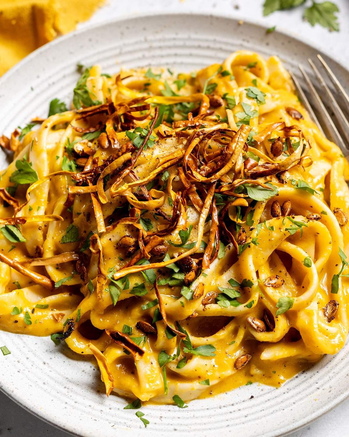 Plated butternut squash pasta with cashew cream sauce, garnished with fresh herbs