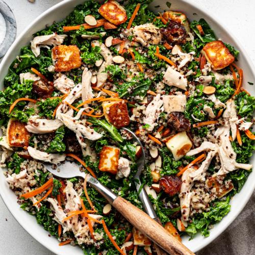 roasted chicken with quinoa and kale served on a wooden table