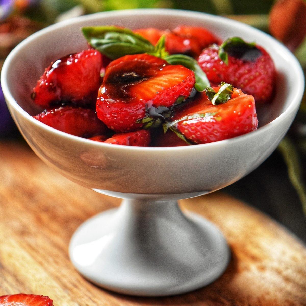 A person preparing the Basil Strawberry Balsamic Glaze Tart in a kitchen setting