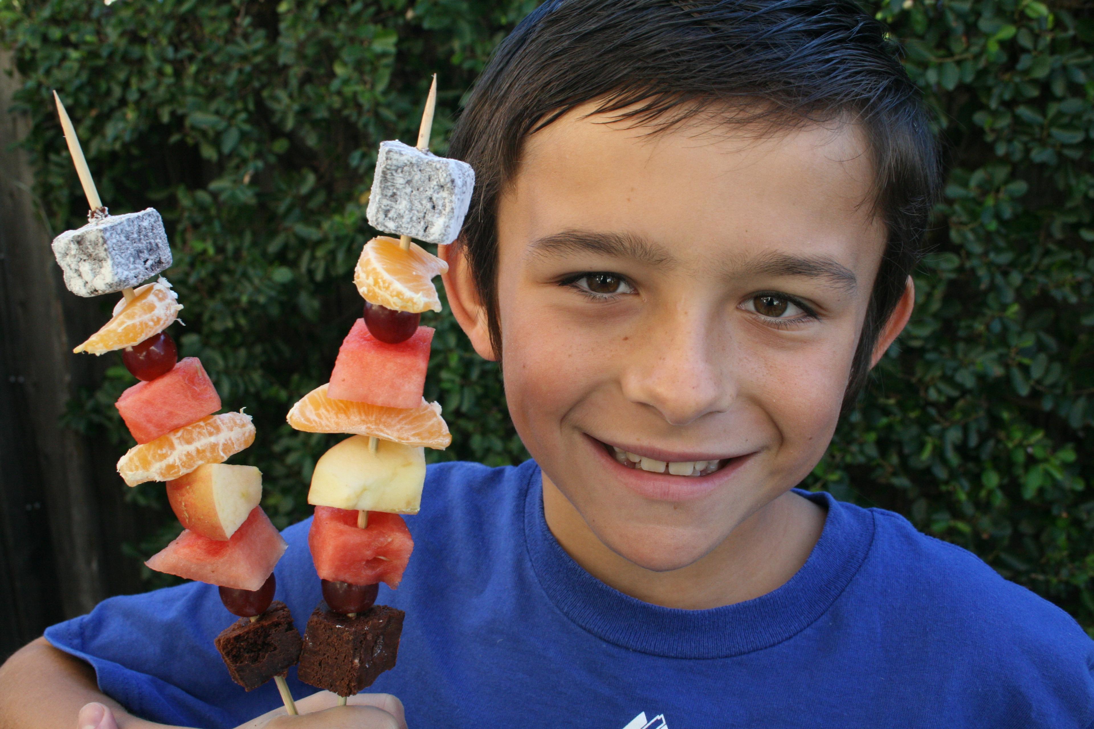A group of children enjoying fruit kebabs outdoors