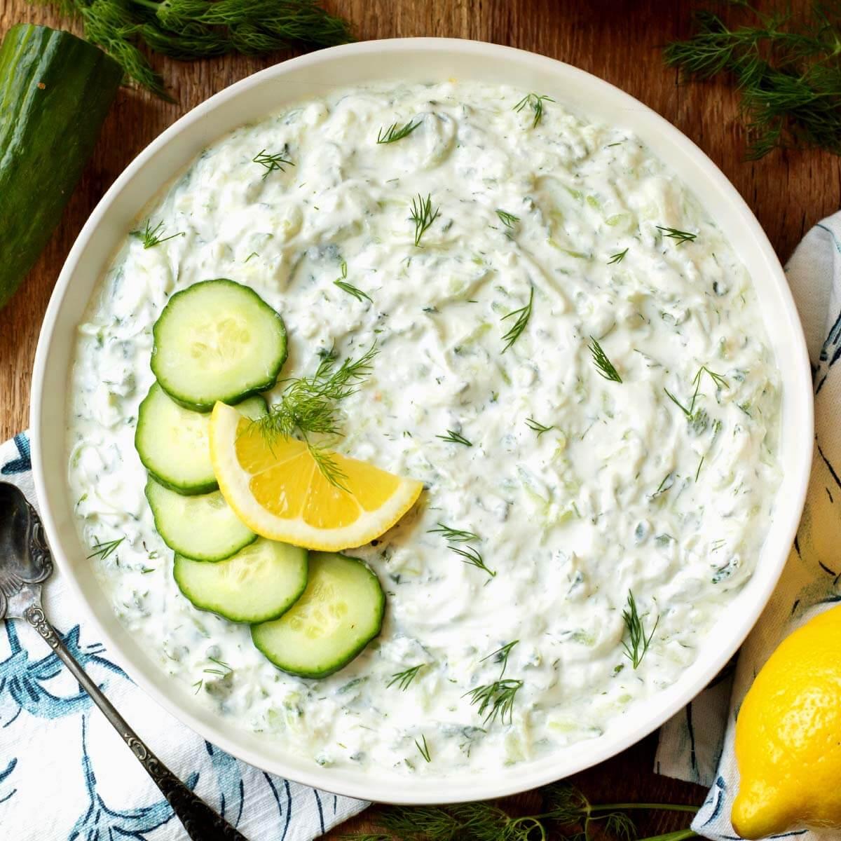 Close-up of creamy homemade tzatziki sauce with fresh dill and grated cucumber in a small white bowl