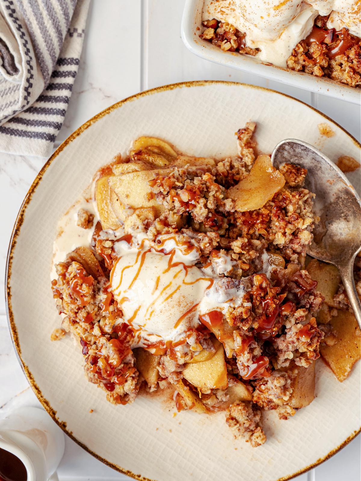 overhead shot of a warm apple crisp with thyme sprigs and a scoop of vanilla ice cream