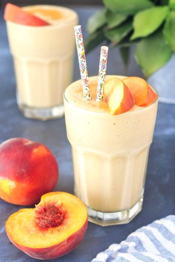a vibrant vanilla peach smoothie in a glass, garnished with a peach slice and a vanilla bean