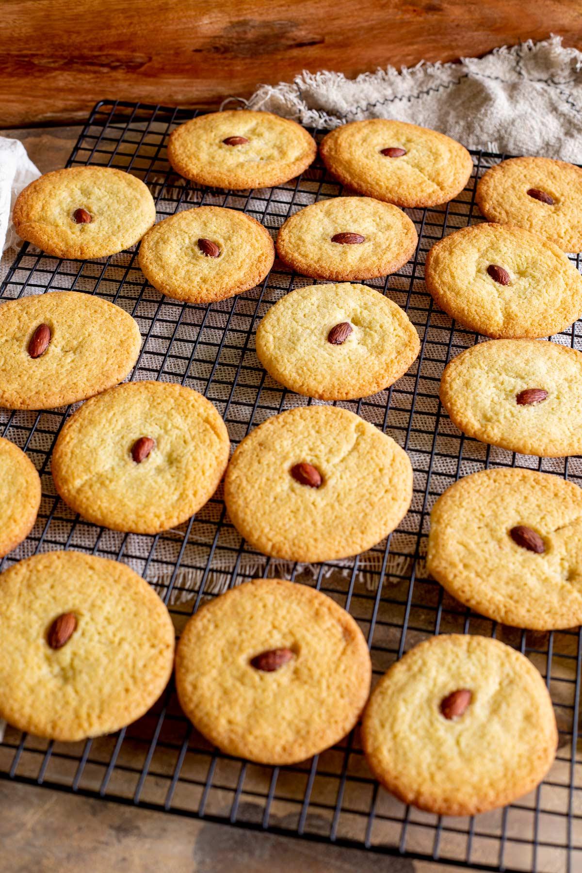Close-up of golden brown almond cookies with crisp edges on a cooling rack