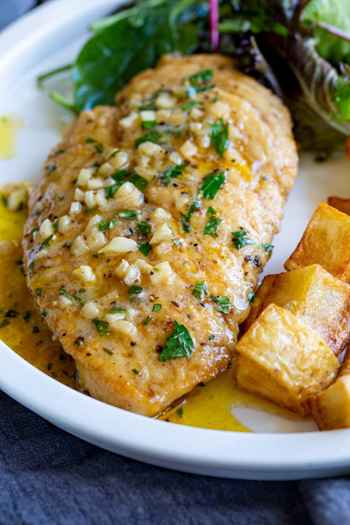 golden pan-seared garlic butter chicken with fresh parsley, close-up