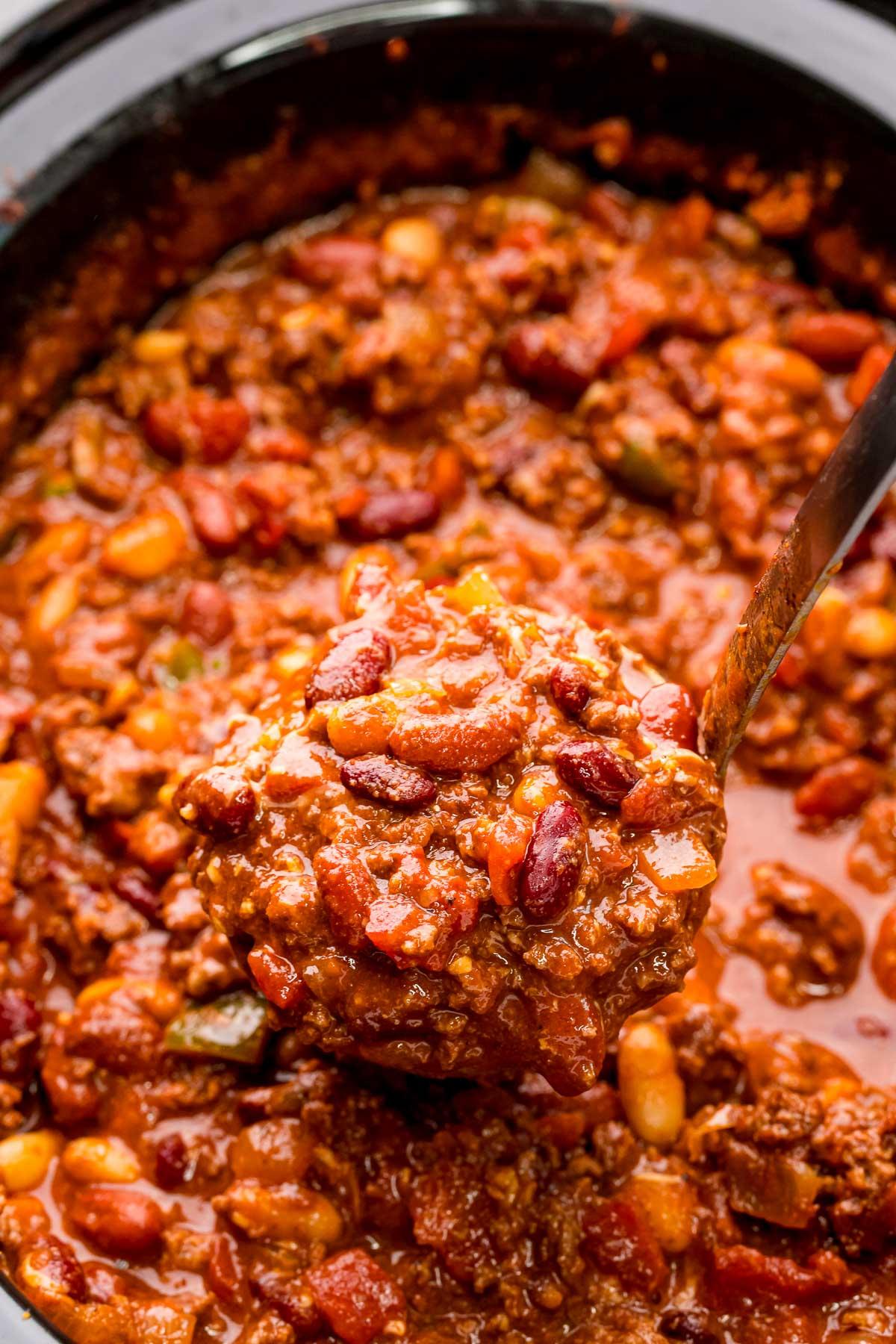 Close-up of slow cooker chili with a ladle scooping out a portion