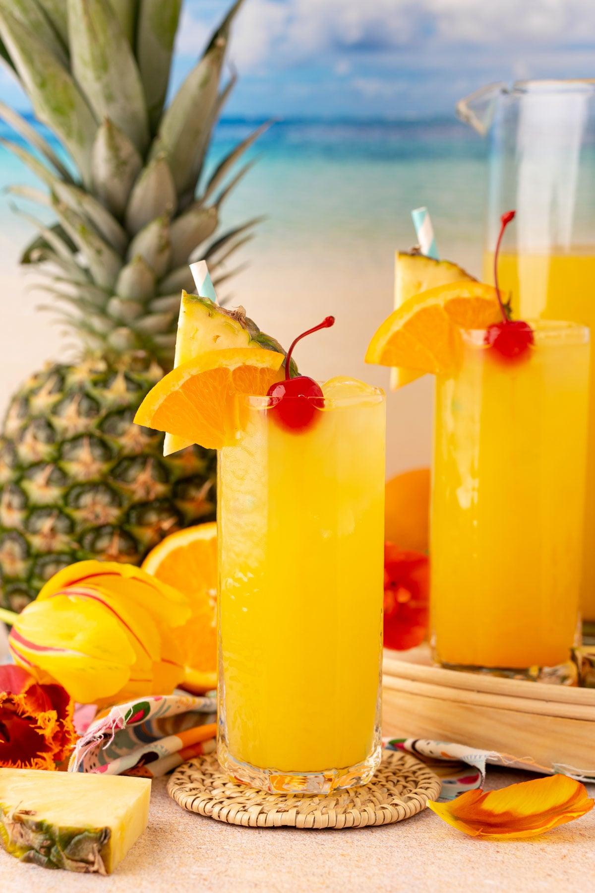 close-up of vibrant nonalcoholic pineapple punch with orange slices and cherries in glass