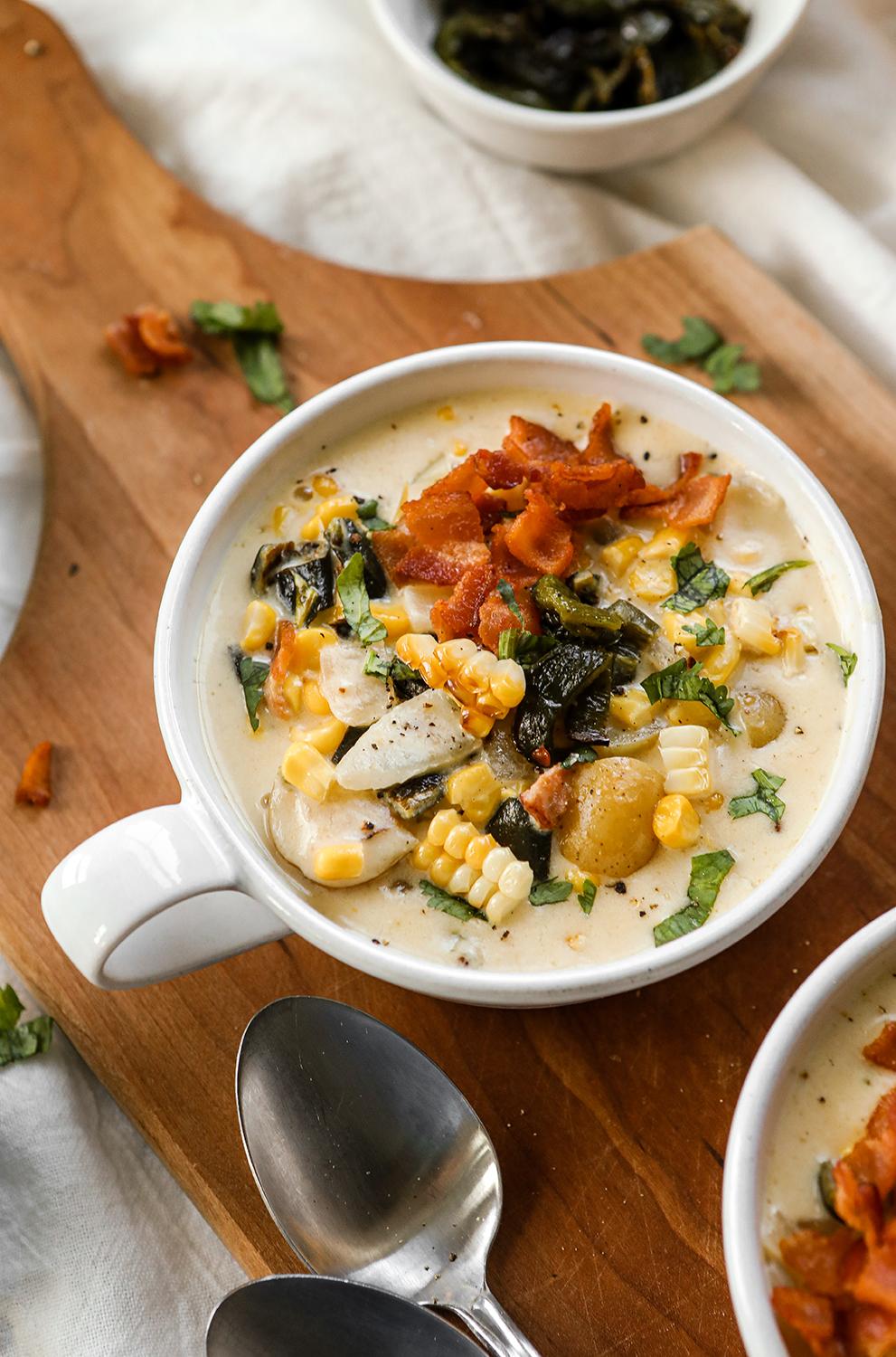 A person enjoying a bowl of roasted corn and poblano soup in a cozy setting