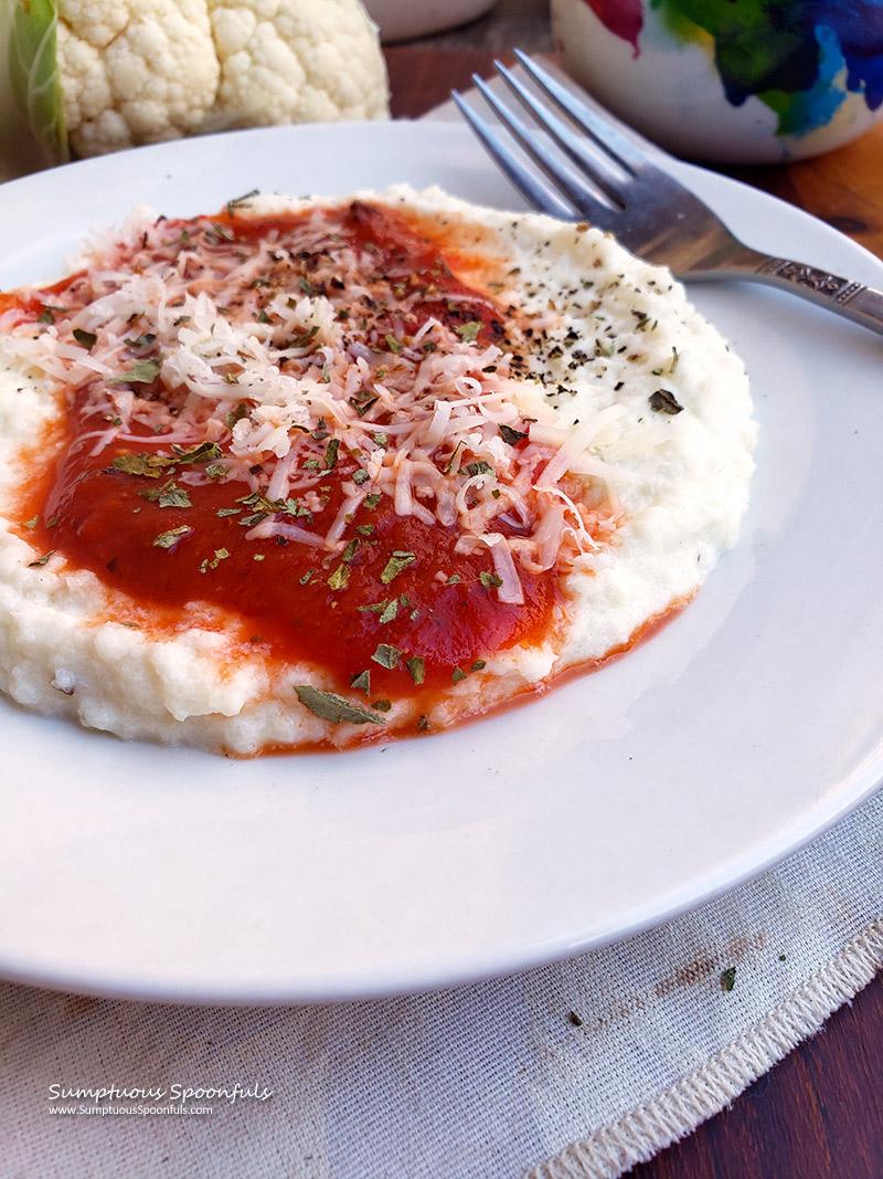 A serving of cauliflower rice polenta with roasted tomatoes plated and garnished with fresh basil.