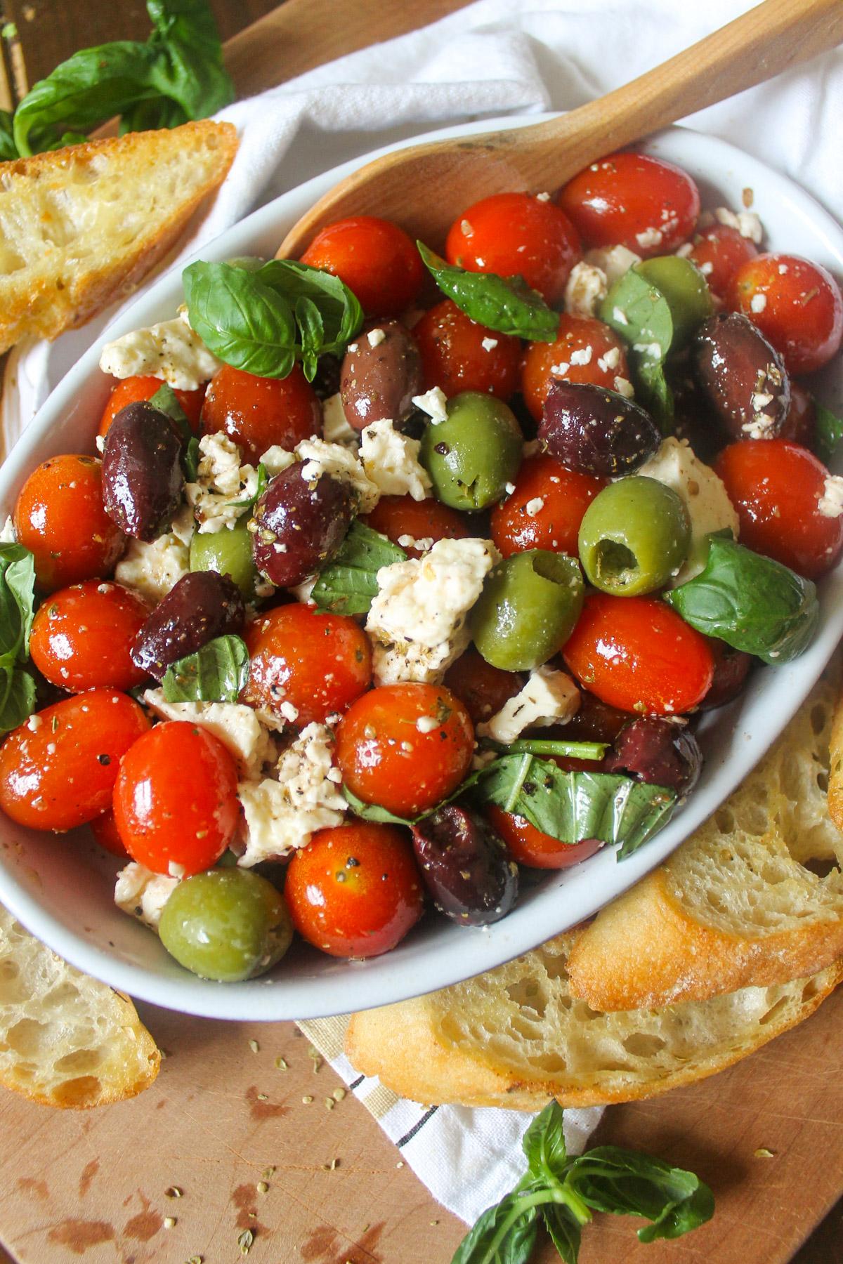 Serving of cherry tomato and olive tagine being garnished with feta