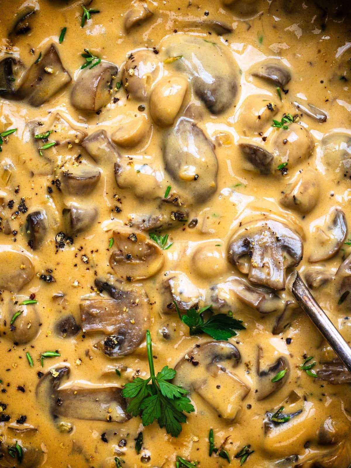 Close-up of a creamy mushroom sauce simmering in a saucepan, with sliced mushrooms visible