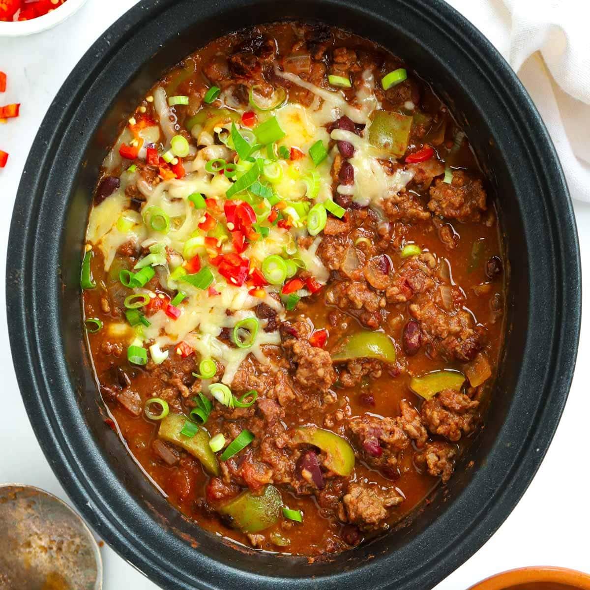 Slow cooker with bubbling chili beef, steam rising