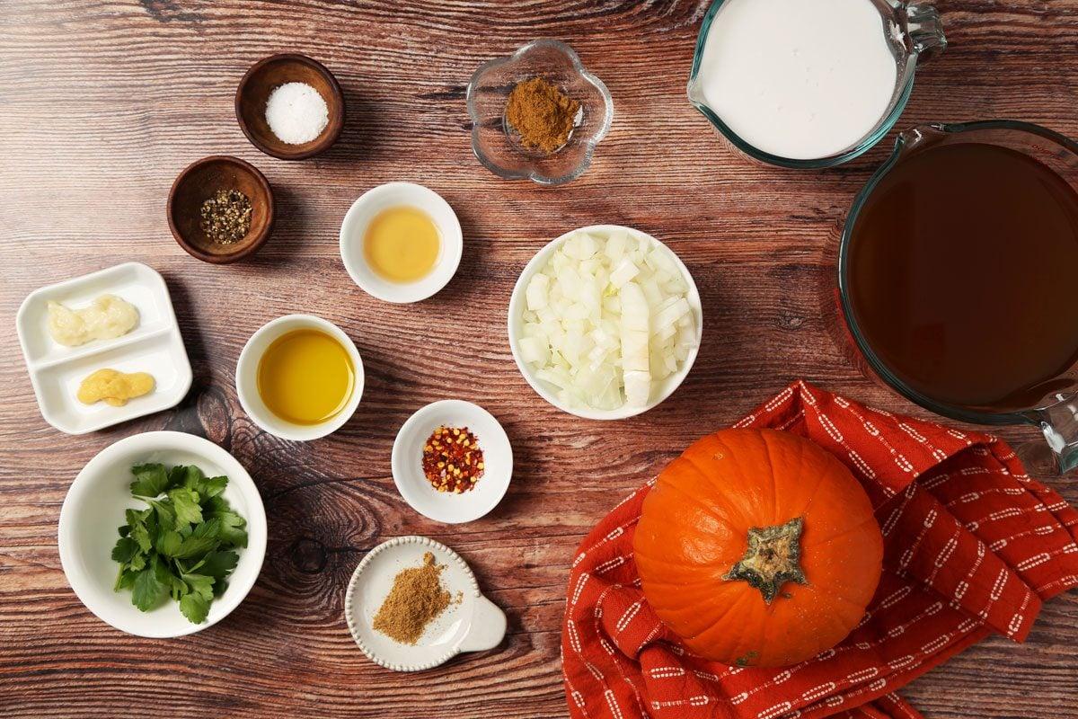 ingredients for pumpkin soup laid out on a wooden table