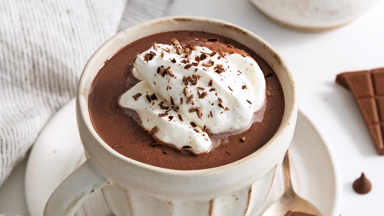 close-up of rich hot chocolate in a mug, with melting whipped cream and chocolate shavings