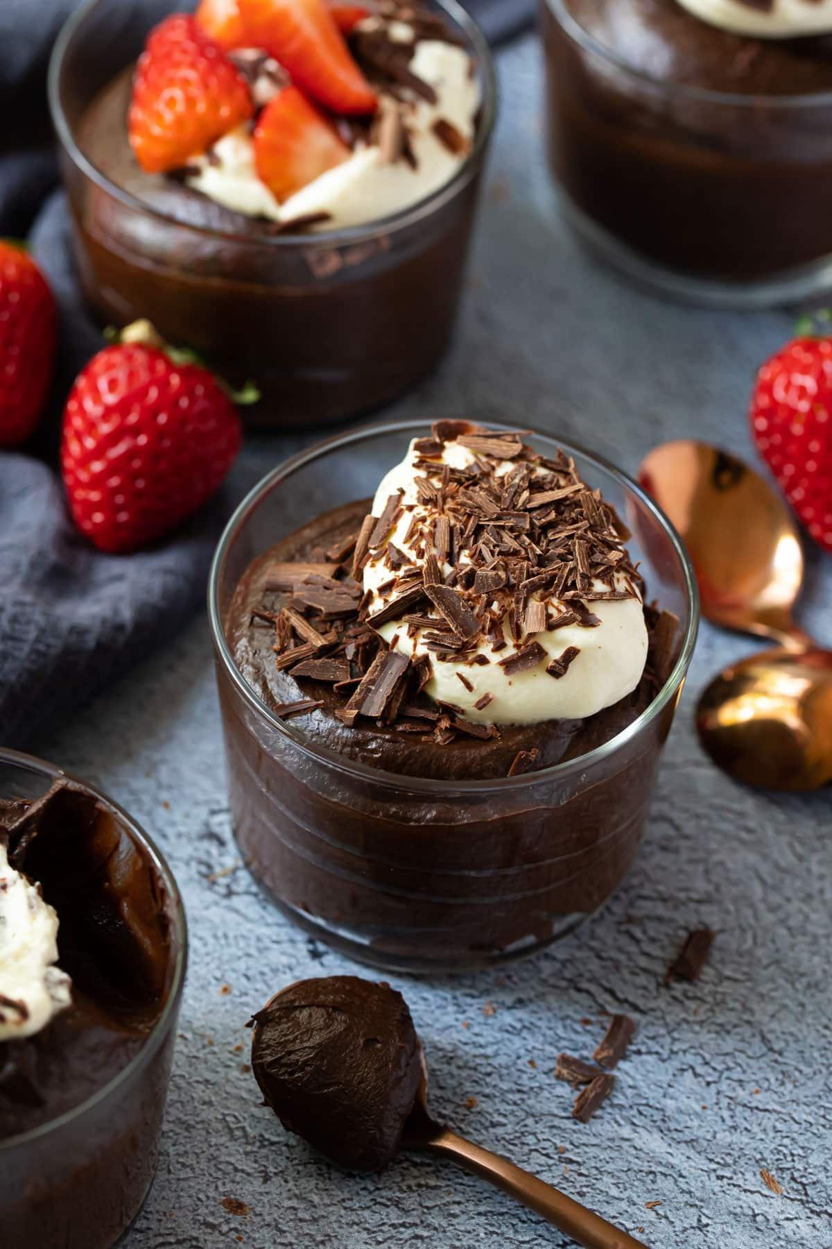 A luscious creamy chocolate mousse made with avocado, served in a glass dish with fresh berries and a dusting of cocoa powder.
