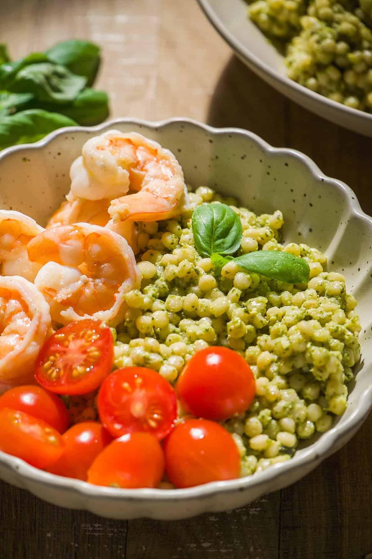 a hand drizzling pesto over a shrimp protein bowl