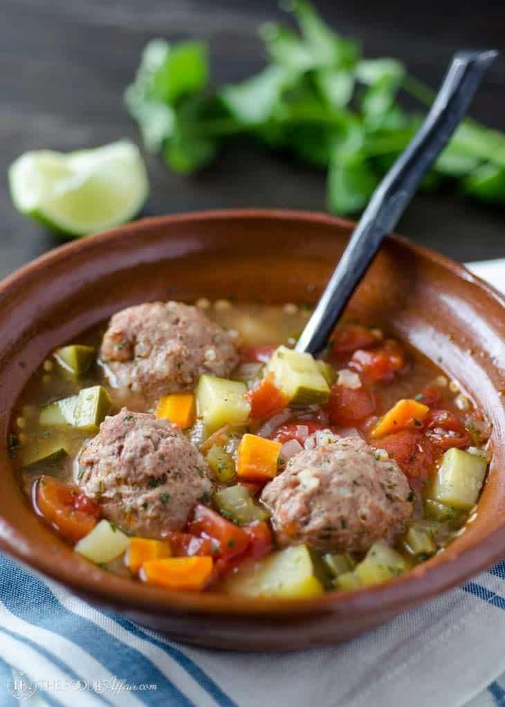 Family enjoying bowls of keto Mexican meatball soup around a dining table