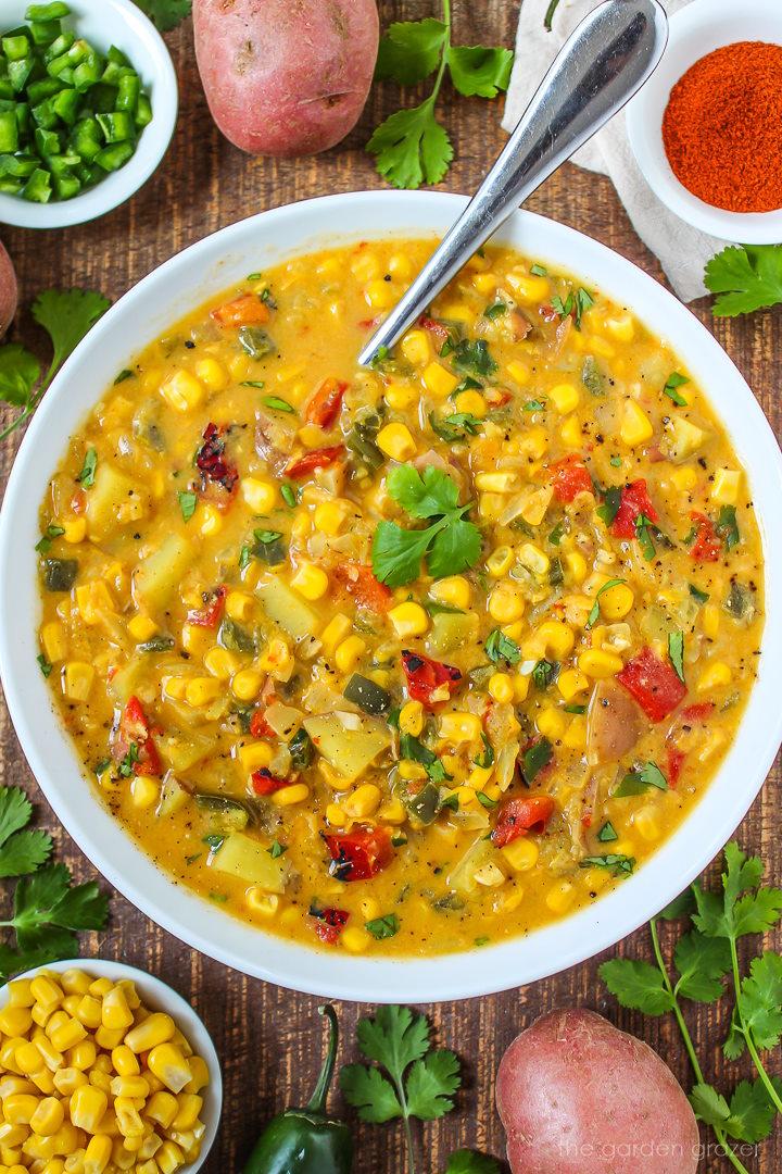 close up view of a bowl of spicy paprika and corn chowder with a spoon