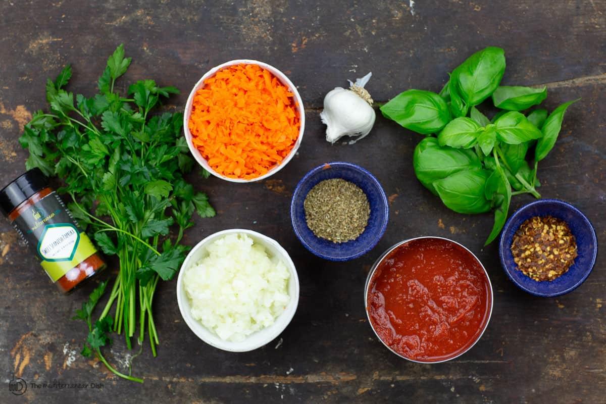 fresh herbs and spices being added to a spaghetti sauce