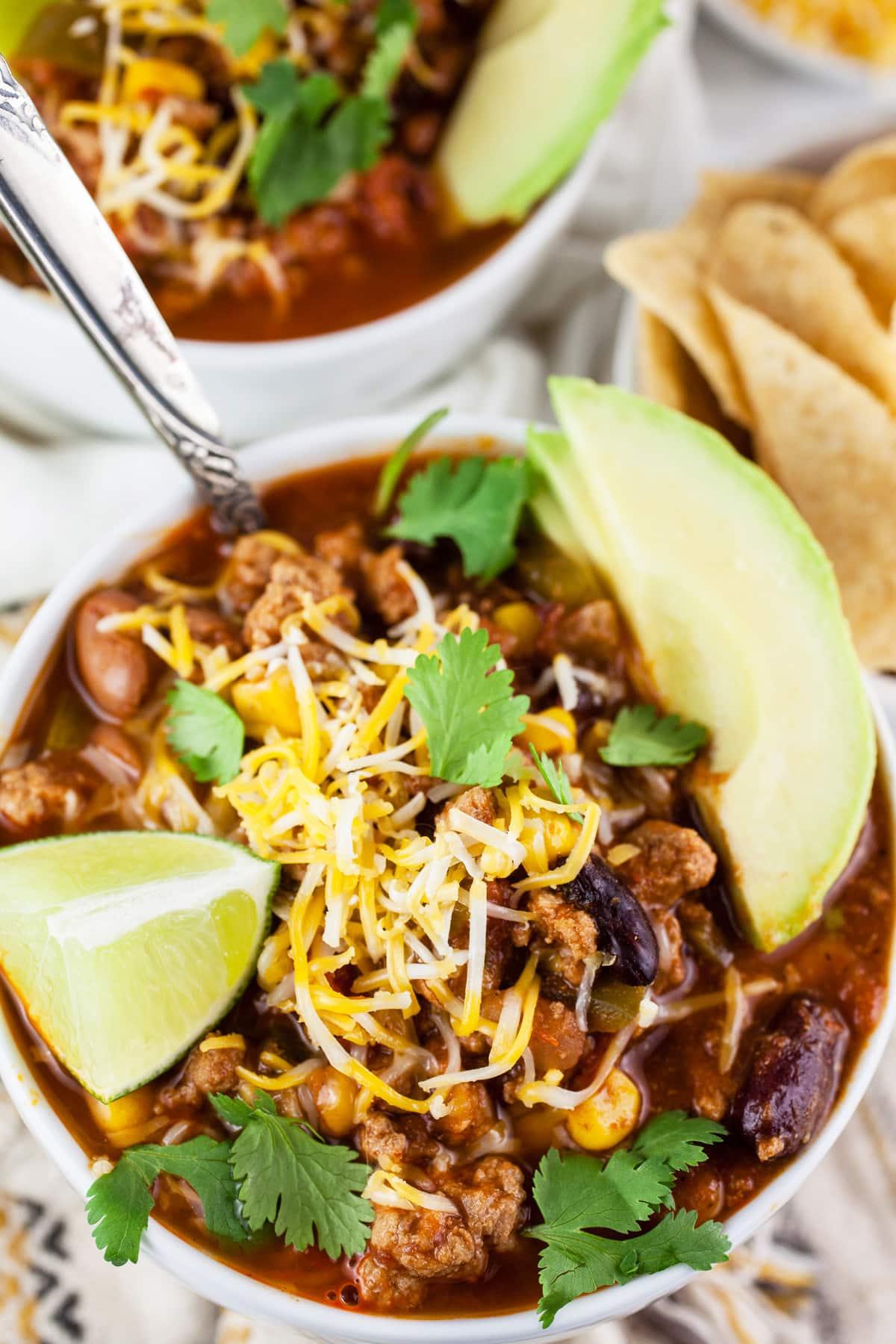 Slow cooker filled with spicy turkey chili garnished with cilantro and lime wedges