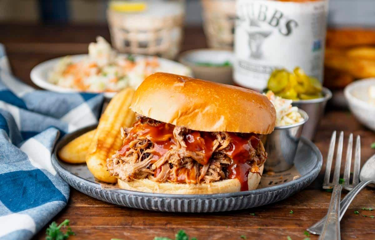 Close-up shot of slow cooker pulled pork with vinegar coleslaw on a rustic wooden table