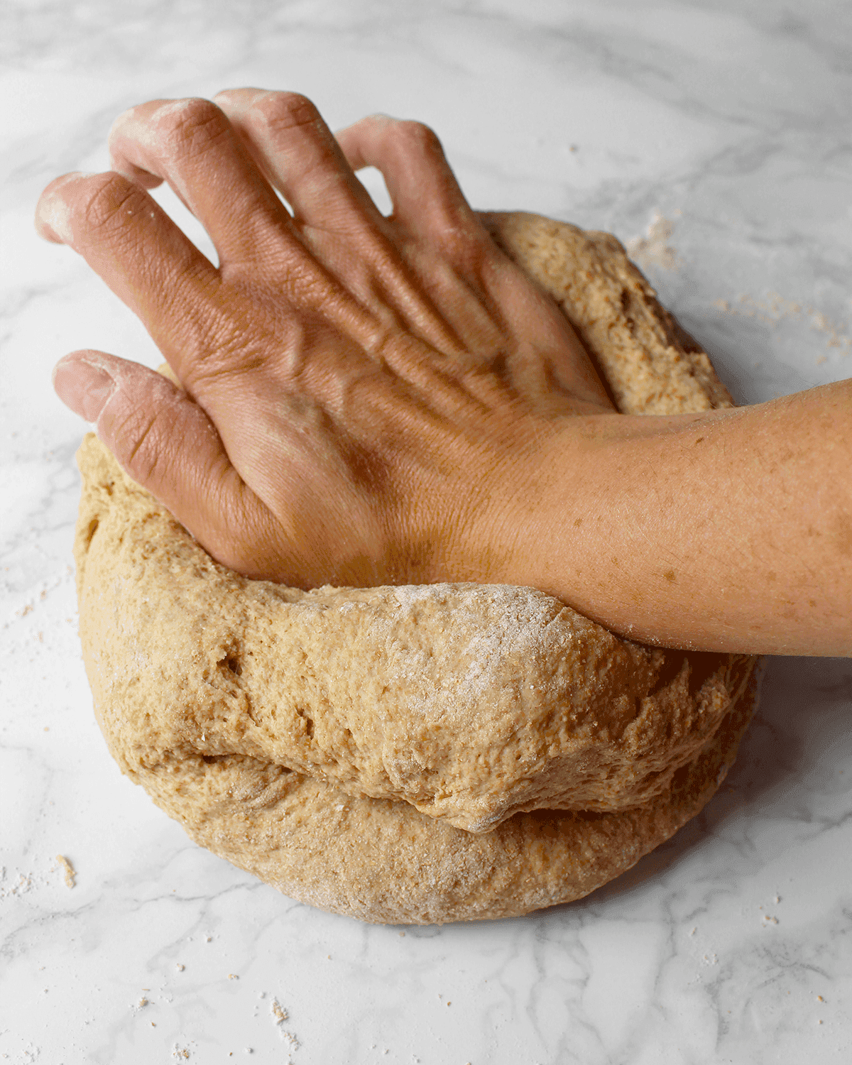 hands kneading whole wheat pizza dough