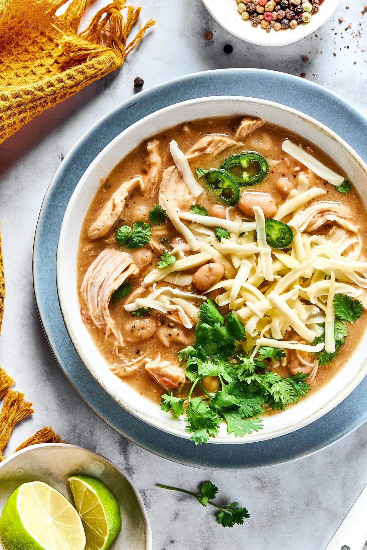 overhead shot of a table setting with bowls of white chicken chili and toppings
