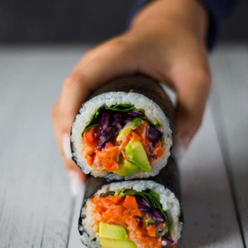 close up of a half eaten seaweed burrito showing layers of filling