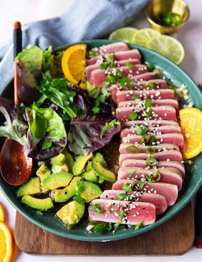 Tuna tataki slices arranged on a plate with sesame seeds and green onions