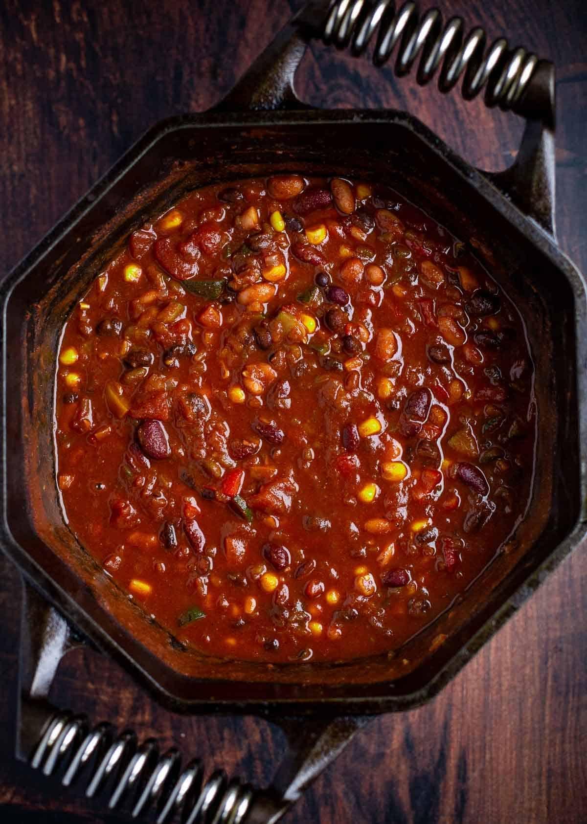 A wide shot of a pot of vegetarian chili simmering on a stovetop.