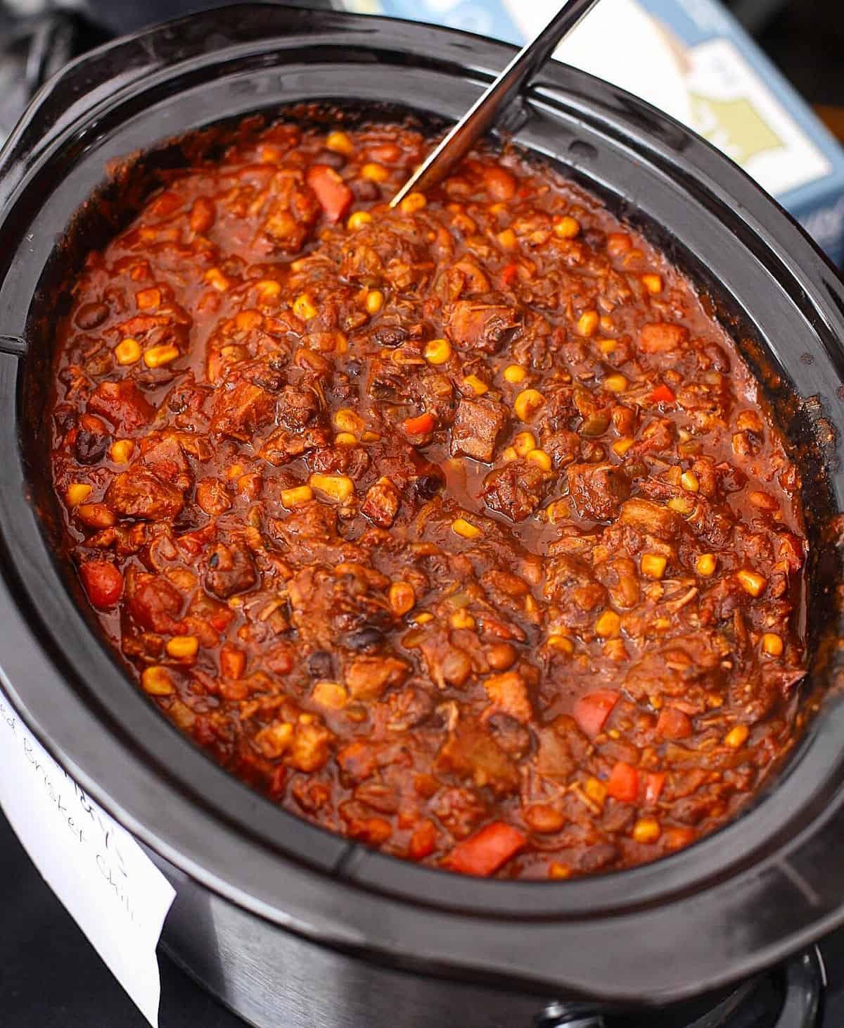 A hearty bowl of BBQ chili with smoke-filled background