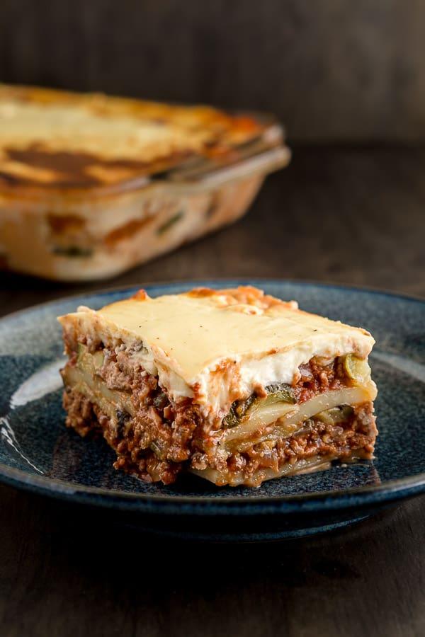 Close-up shot of a slice of moussaka, showcasing the layers and the red wine sauce