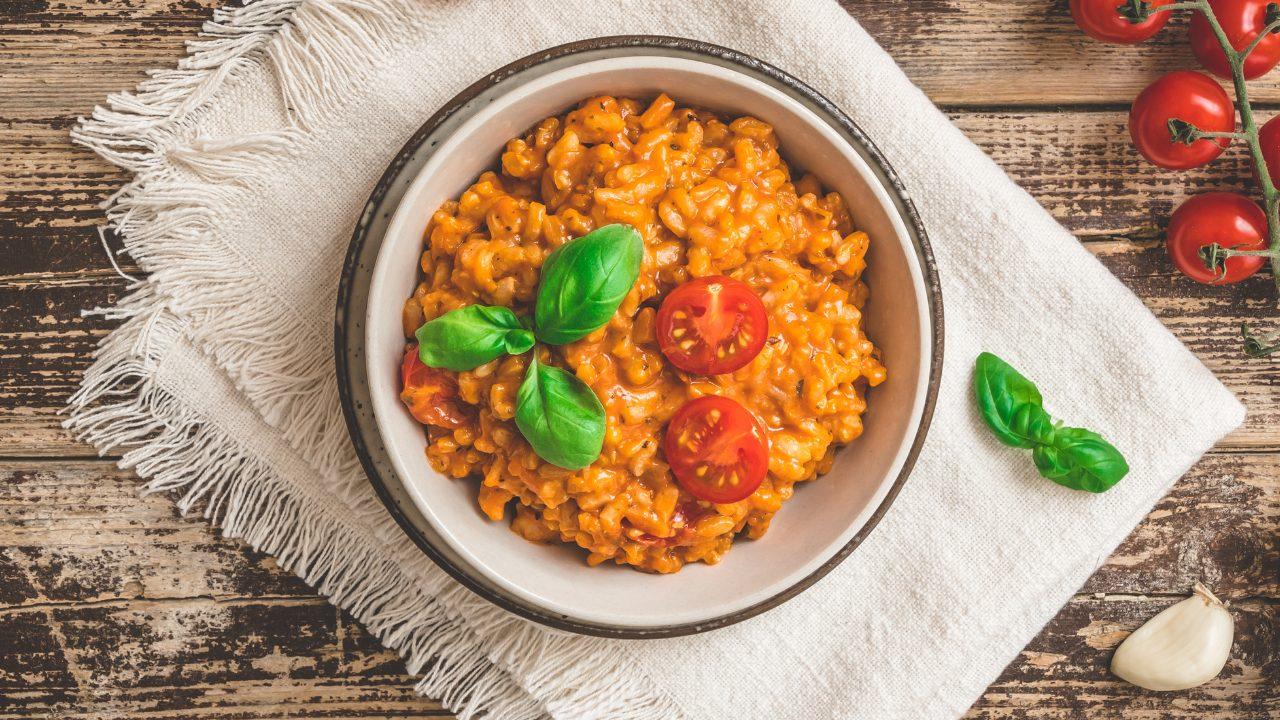 overhead shot of sun-dried tomato and olive risotto in a ceramic bowl