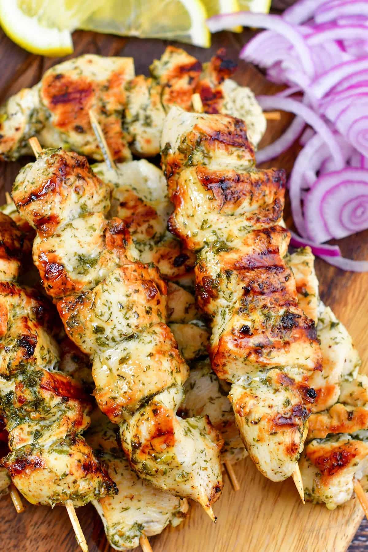 Close-up shot of chicken souvlaki skewers topped with avocado crema and fresh herbs