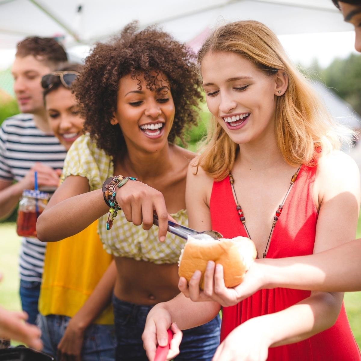 A group of friends laughing and enjoying fruit kebabs outdoors