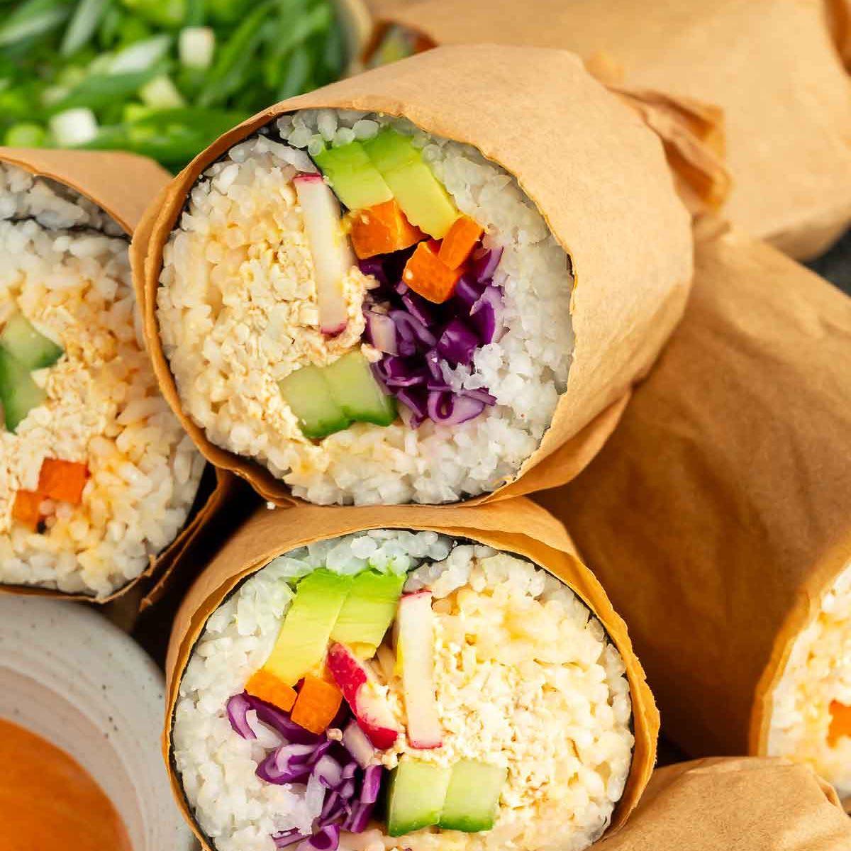 a vibrant, colorful sushi burrito being held, showcasing the fillings