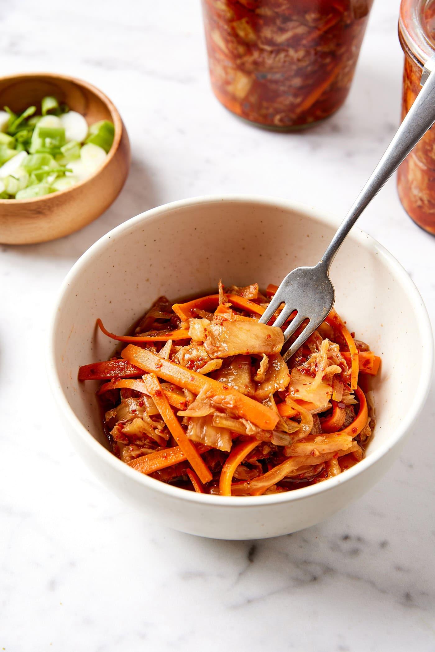 A close-up shot of vibrant, colorful kimchi and orange ingredients