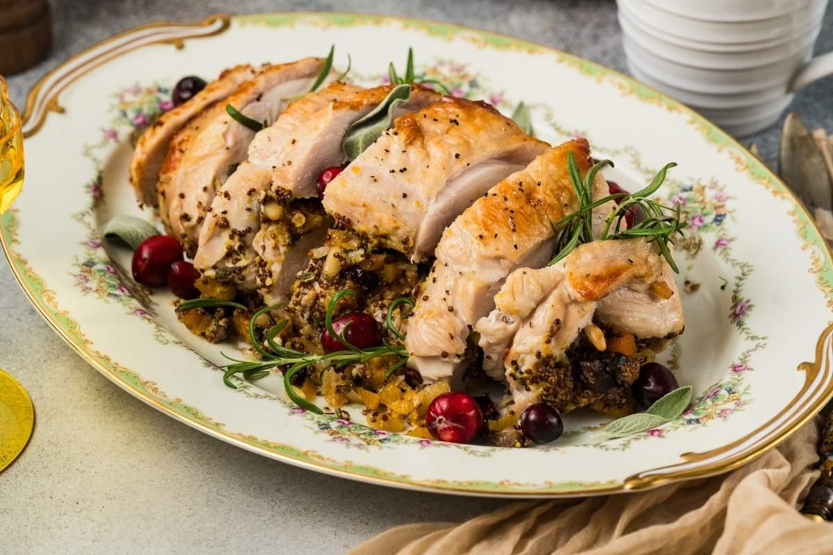 golden brown herb crusted turkey breast with carving knife and juicy slices on a platter